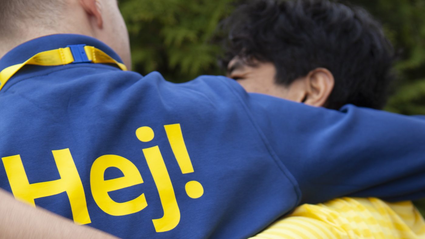 Picture of two IKEA colleagues from behind holding each other/hugging and laughing.