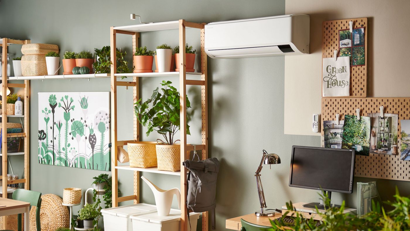 A living room in the color green with furnishings from IKEA where you can also see a heat pump hung on the wall.