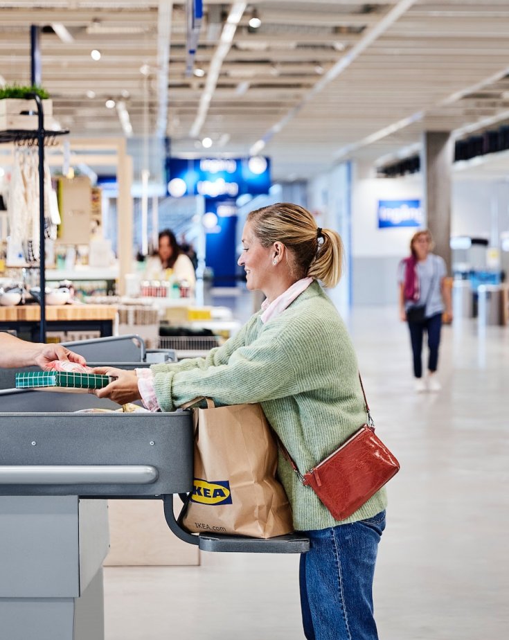 Customer shops at IKEA department store and stands at the conveyor belt to pack his goods.