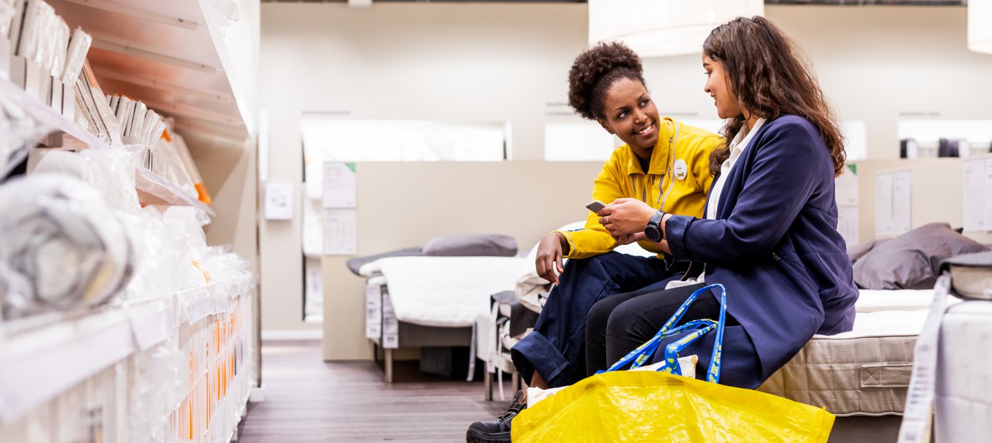 IKEA employee helping a customer in the bedroom department.