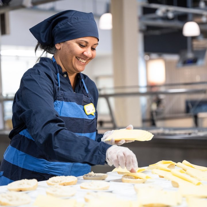 IKEA employee smiles and stands in the IKEA kitchen as she prepares food for customers inside a department store.