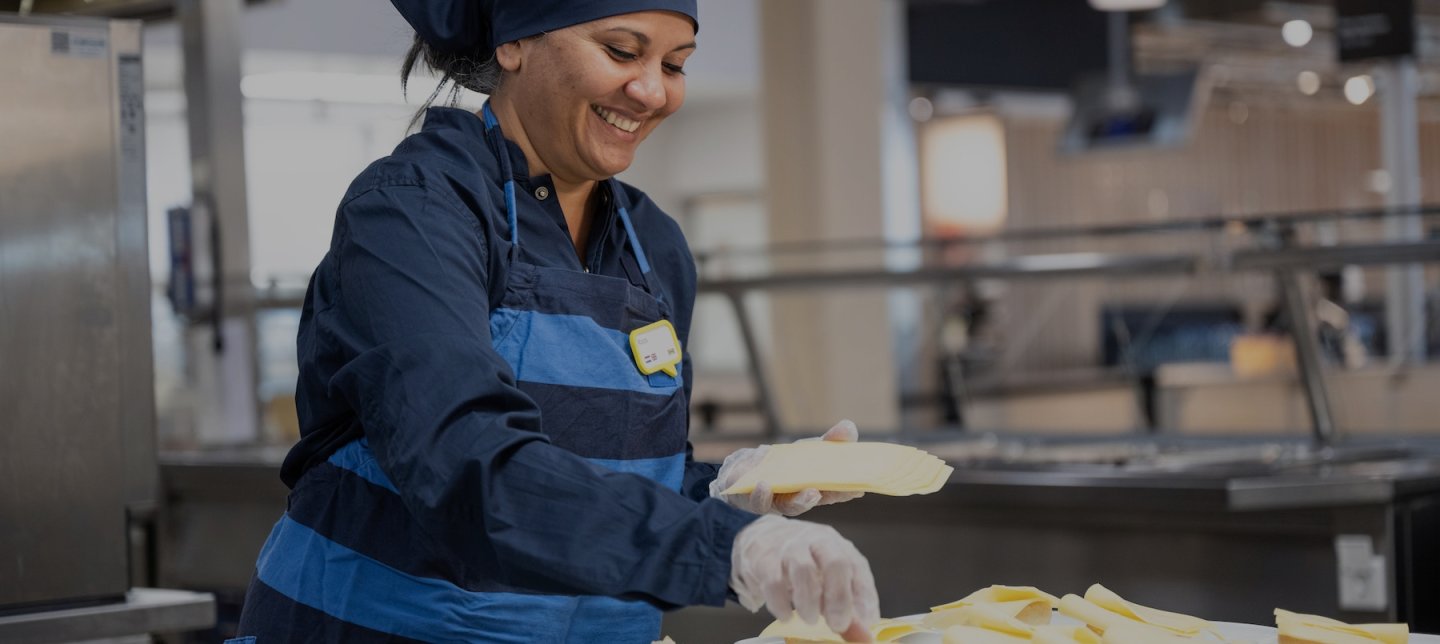 IKEA employee smiles and stands in the IKEA kitchen as she prepares food for customers inside a department store.