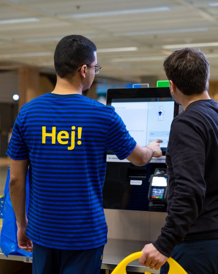 IKEA employees help a customer with self-scanning of payment in a department store.