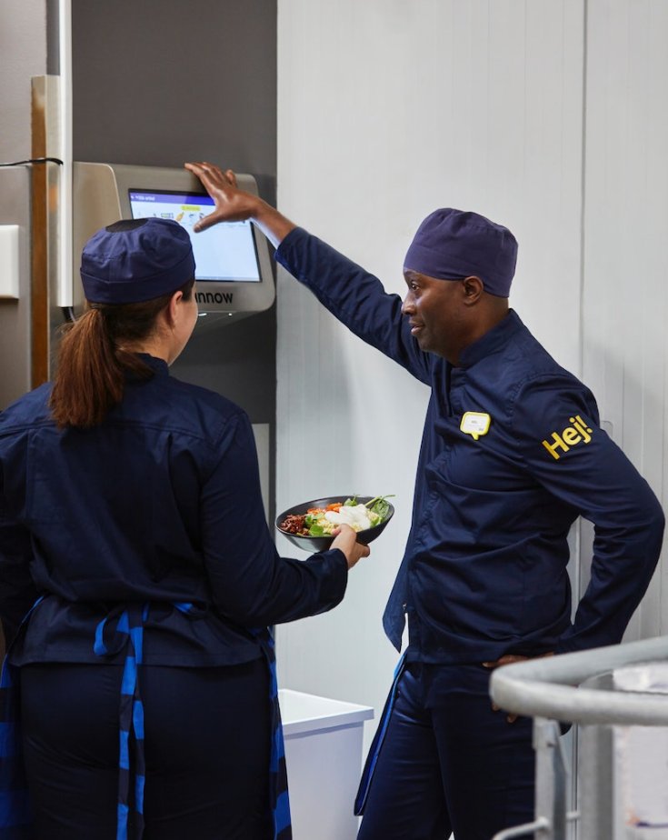 Two IKEA employees talk to each other inside a kitchen.
