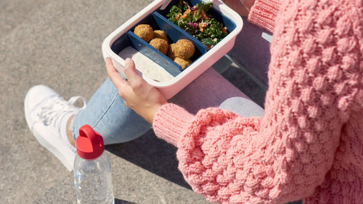 Woman enjoying her lunch on a sunny day in an IKEA plastic food container.
