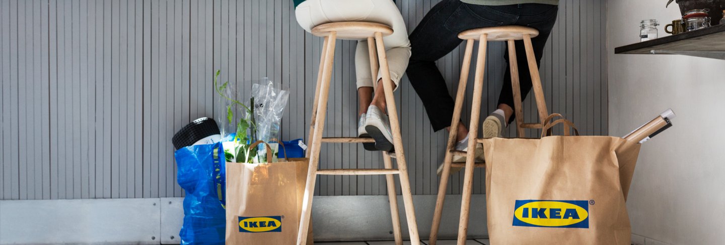 Friends sitting at a cafe with several bags from the IKEA store.