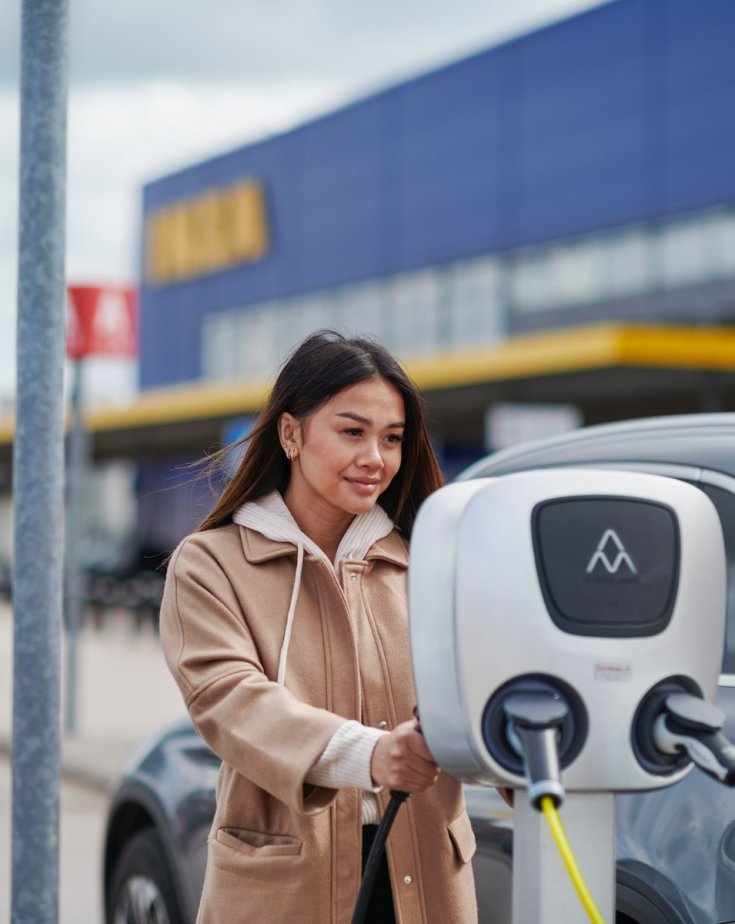 Customer charges his car at an electric charging pole in an IKEA parking lot.