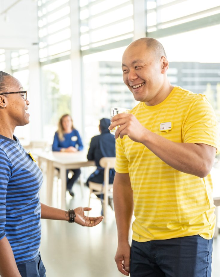 Two employees are talking to each other and laughing inside a department store.