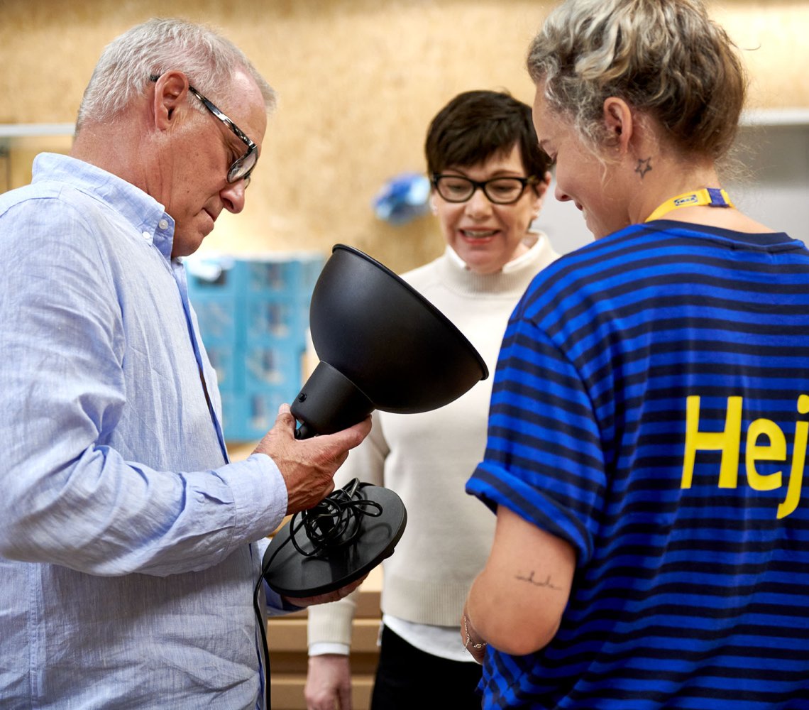 Customers and IKEA workers discuss a lamp inside an IKEA department store.