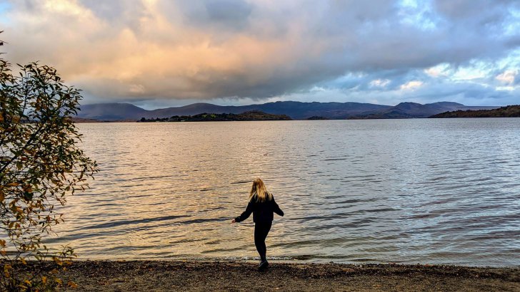 woman standing by a lake.